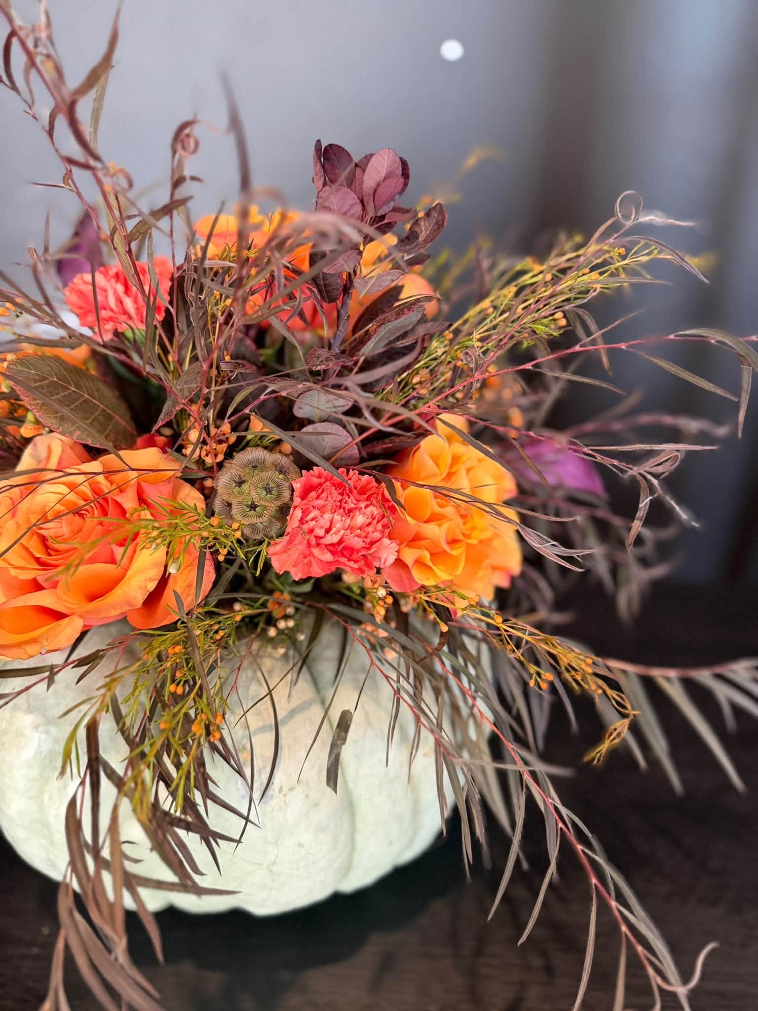 A wide autumn centerpiece with orange blooms