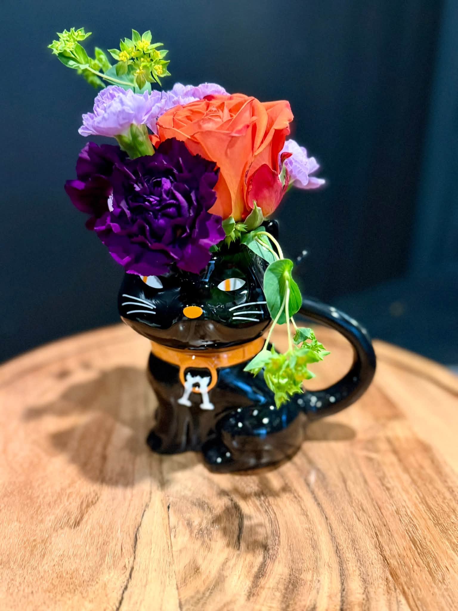 Purple and orange flowers in a black Halloween mug