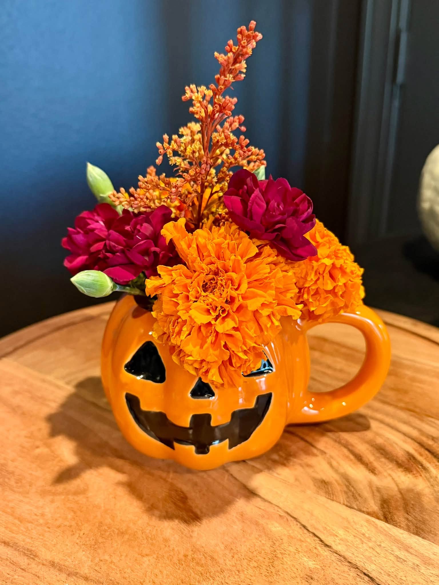 Orange autumn flowers in a jack-o-lantern mug